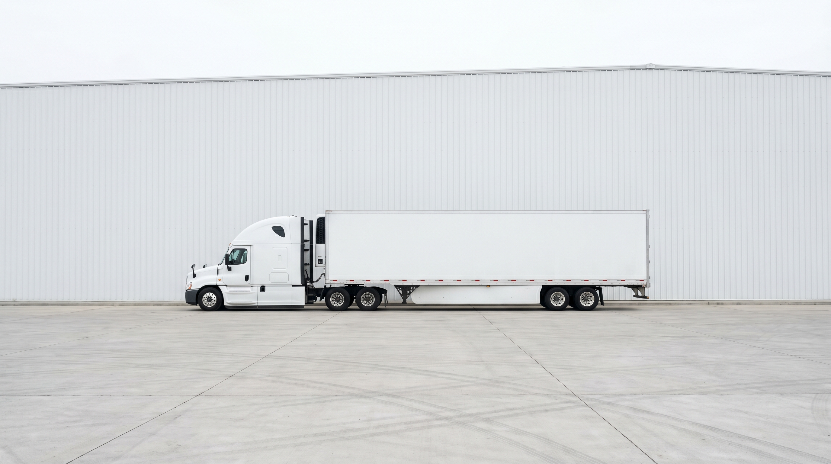 White semi-truck parked in front of a warehouse